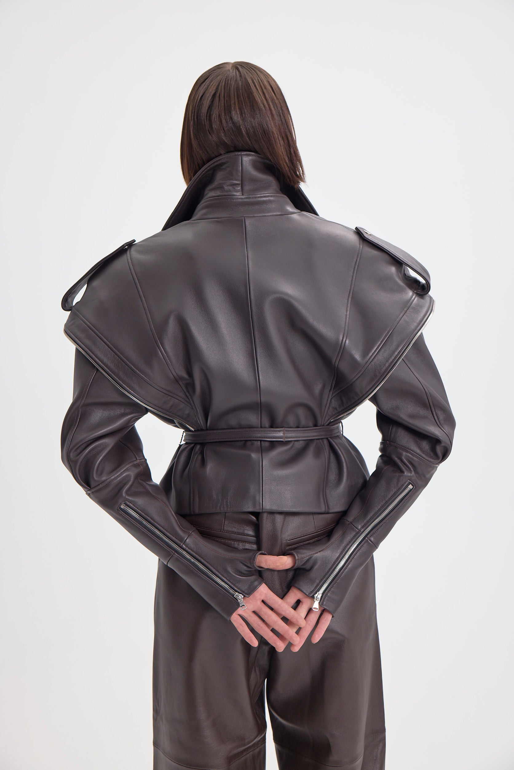 Back view of the DREJANI 'Sogno di Cacao' dark brown leather jacket with unique design elements and belted waist.