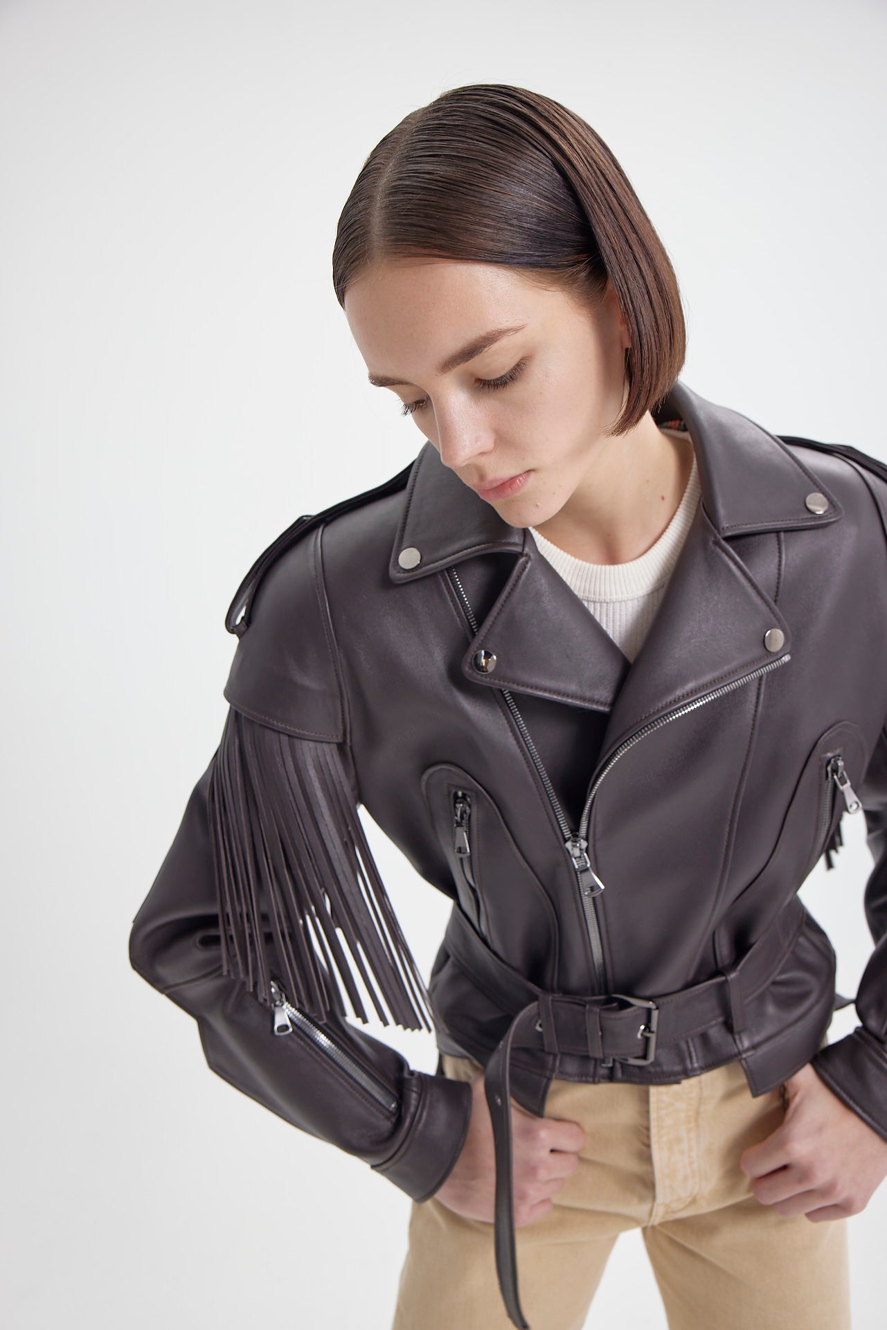 Detailed view of Brown Fringe Leather Jacket by Drejani with zippered pockets and belted waist.