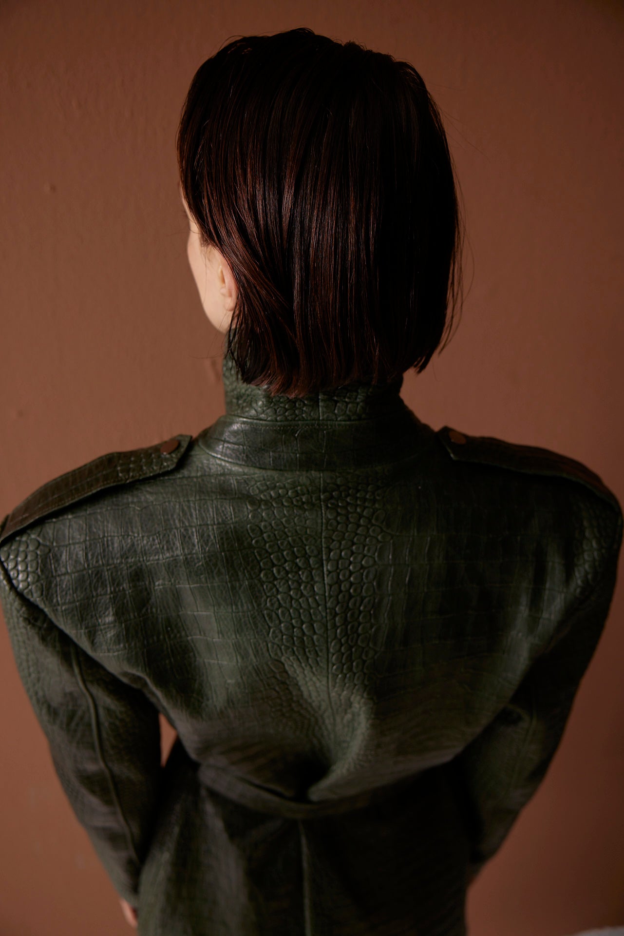 High-quality green croco-embossed leather coat with a belt, featuring a detailed back view, worn by a model.